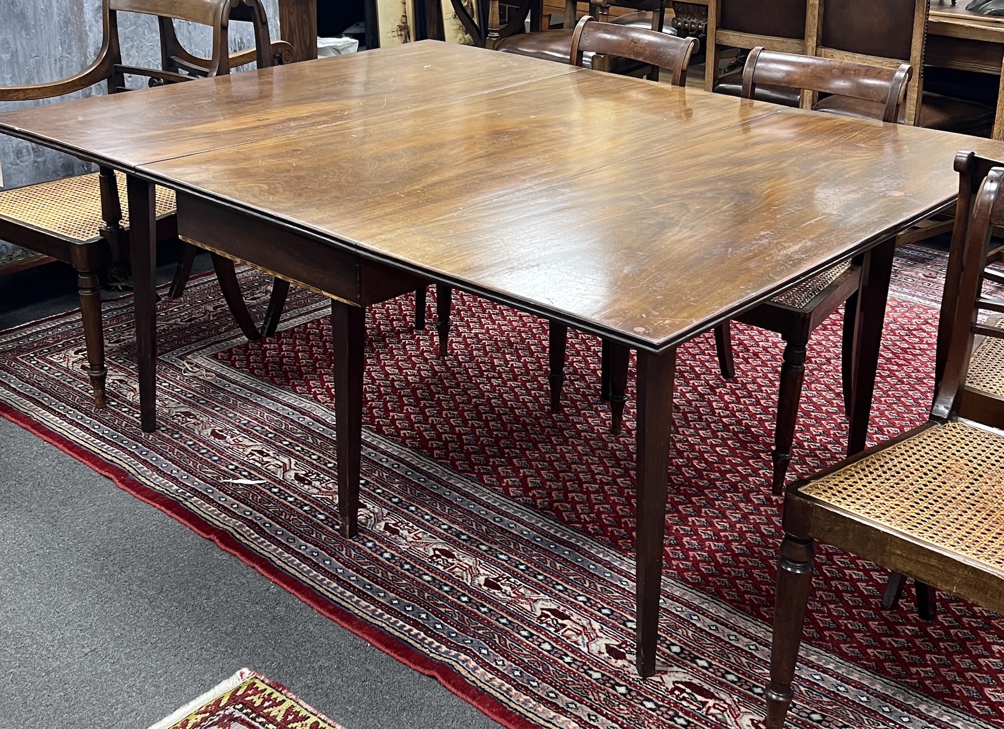 A George III mahogany drop leaf extending dining table on square tapered legs, 165cm extended, depth 130cm, height 74cm